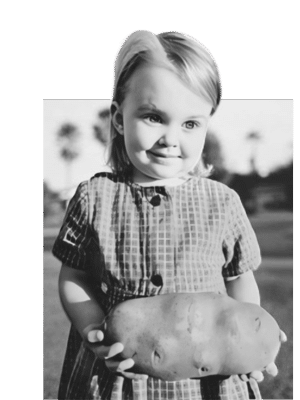 our mantra an old black and white photo of little girl holding a giant potato and smiling
